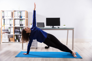 Young Businesswoman Doing Stretching Exercise On Exercise Mat At Workplace