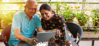 Senior Indian/asian couple accounting, doing home finance and checking bills with laptop, calculator and money while sitting on sofa/couch or dining table at home