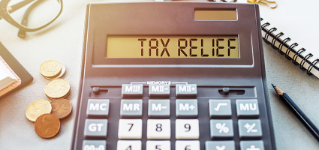 Word TAX RELIEF. Written on a calculator on an office desk.