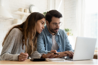 Focused young couple calculating bills, discussing planning budget together, serious wife and husband looking at laptop screen, using online banking services and calculator, checking finances