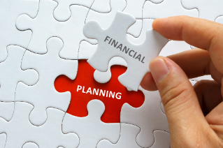 Hand holding piece of jigsaw puzzle with word FINANCIAL PLANNING.