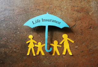 Paper family of four under a Life Insurance paper cutout umbrella                               