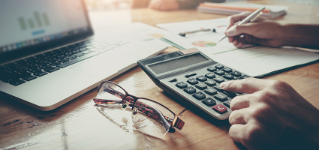 Close up Businessman and partner using calculator and laptop for calaulating finance, tax, accounting, statistics and analytic research concept