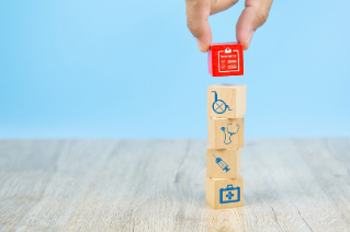 Close-up hand choose a red wooden toy blocks with insurance policy icon for health insurance concepts.